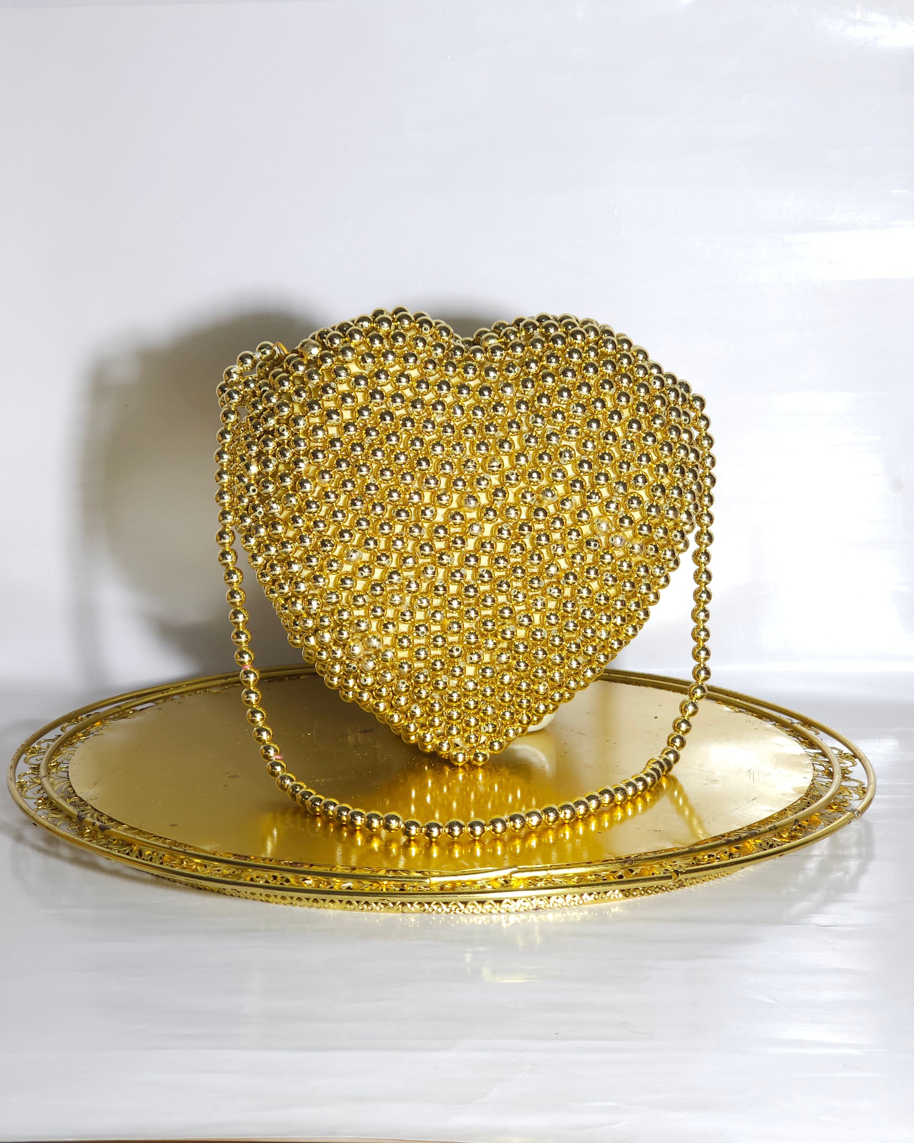 Gold heart-shaped handbag with beaded details on a white background