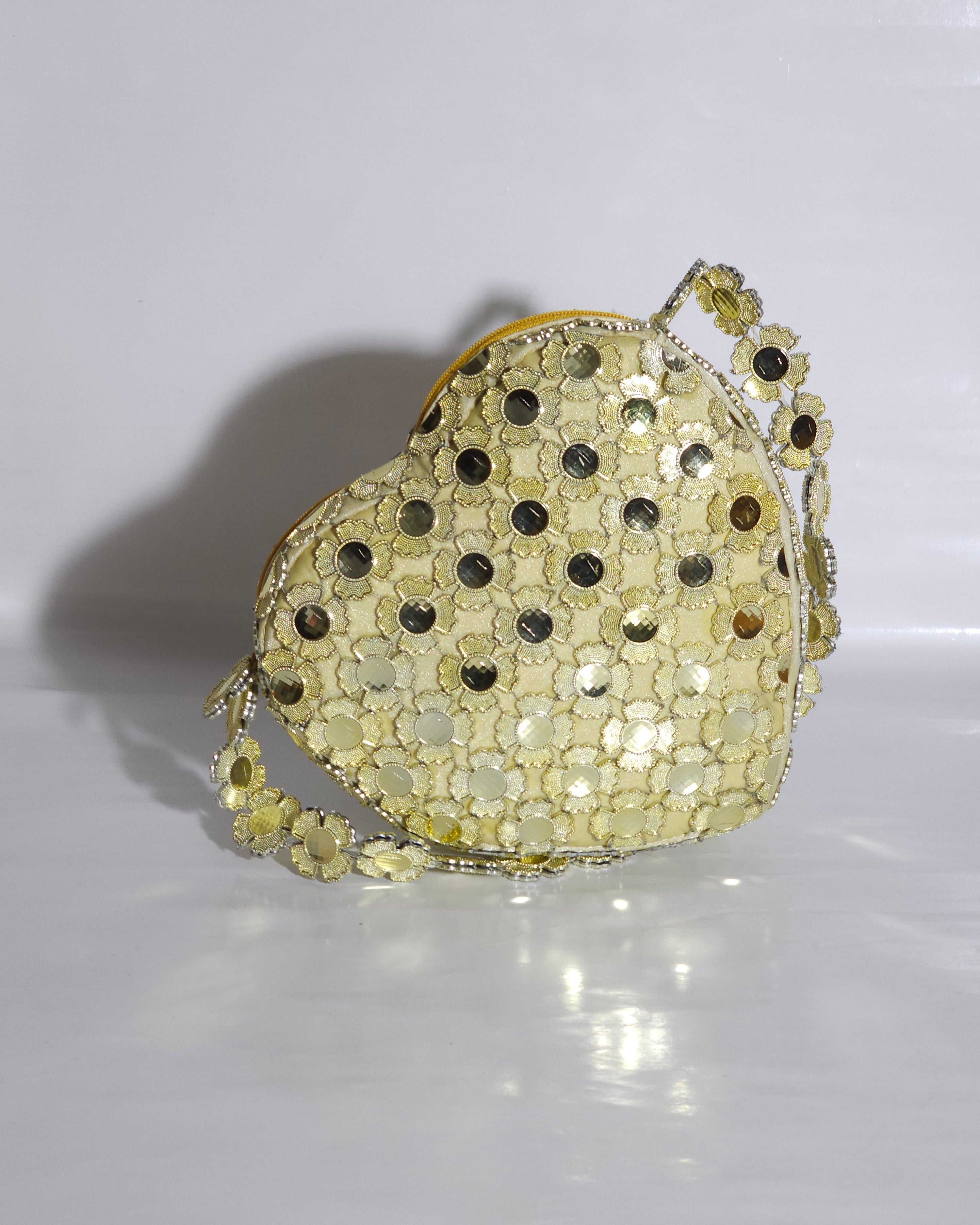 Gold sequin handbag with black dots on a white background